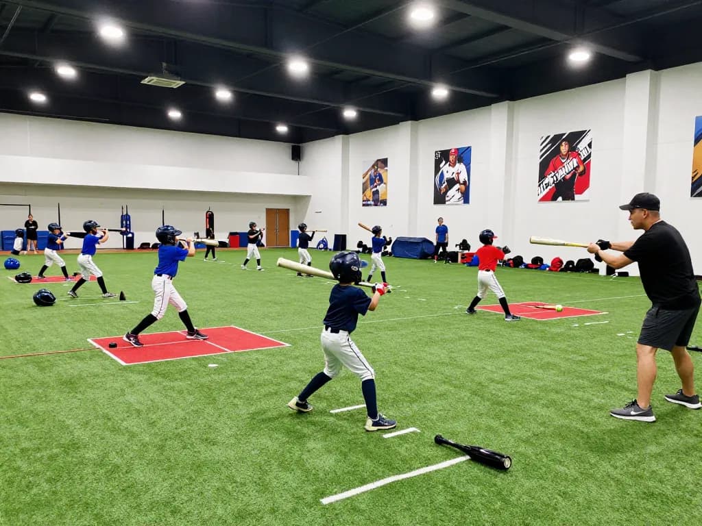 Young athletes training at Hitclub baseball facility, demonstrating hitting techniques with coaching.